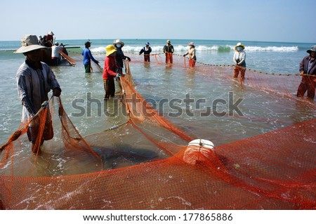 BINH THUAN, VIETNAM- JAN 22: Team work of fisherman on beach, group of people pull fishing net to catch fish, stand in row, person move to seashore, crowded atmosphere, fresh air,Viet Nam, Jan22, 2014