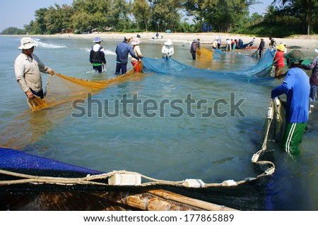 BINH THUAN, VIETNAM- JAN 22: Team work of fisherman on beach, group of people pull fishing net to catch fish, stand in row, person move to seashore, crowded atmosphere, fresh air,Viet Nam, Jan22, 2014