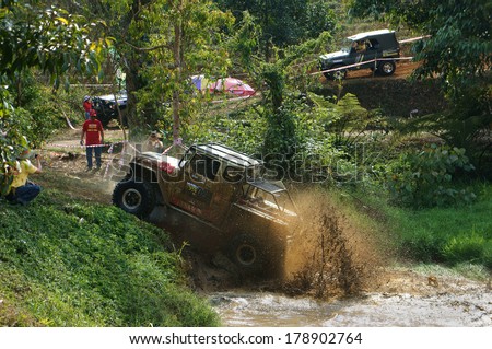 DAMBRI, VIET NAM- FEB 23, 2014: Racer offroad at terrain racing car competition, motor wade cross lake, splash mud, competitor  adventure in strong spirit, audience on lakeshore, VietNam