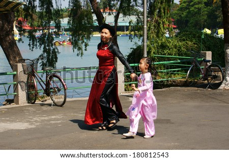 HO CHI MINH CITY, VIET NAM- MARCH 8: Mother holding hand unidentified children walking in park with smile face and happiness, two people in Vietnamese traditional dress, Vietnam, March 8, 2014
