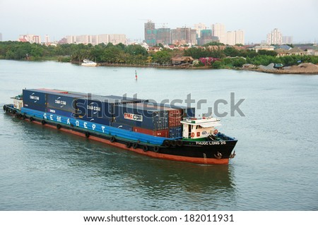 HO CHI MINH CITY, VIET NAM- MARCH 12: Maritime transport on river, vessel loading container on water, residential and apartment at riverside, scene of industrial city, Vietnam, March 12, 2014