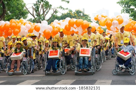 HO CHI MINH, VIET NAM- APRIL 6: Group of invalid people sitting on wheelchair in a row with young volunteer on street, begin charitable activity event for handicapped community, Vietnam, April 6, 2014