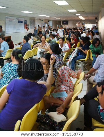 HO CHI MINH CITY, VIET NAM- APRIL 4: Crowd of people sitting and waiting to examine health, sick patient sit on bench at public hospital, Saigon, Vietnam, April 4, 2014