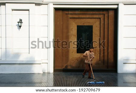 HO CHI MINH CITY, VIETNAM- MAY 12: Young man working on five star hotel lobby, he wear employee uniform, cleaning tile floor, luxury hotel with white wall, wooden door, Saigon, Viet Nam, May 12, 2014