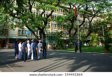 HO CHI MINH CITY, VIETNAM- MAY 19: Group of doctor and nurse standing with solemn spirit, toward flagpole, trooping the colour, sing natinal anthem in hospital yard, Saigon, Viet Nam, May 19, 2014