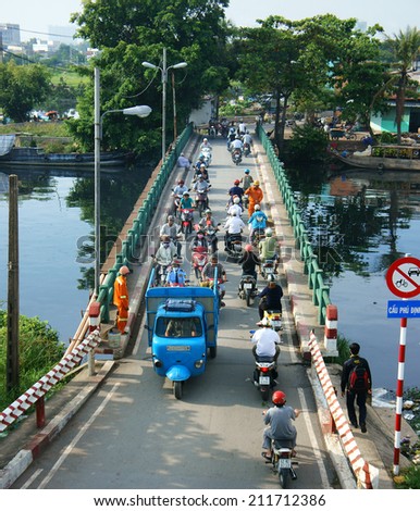 HO CHI MINH CITY, VIETNAM- AUG 18:  Group of vehicle moving on overpass to cross polluted river, people wear helmet, ride motorbike, Phu Dinh bridge cross canal, Vietnam, Aug 18, 2014