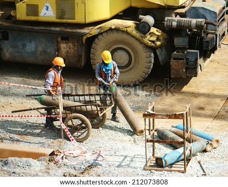 HO CHI MINH, VIETNAM- AUG 9 : Vietnamese construction worker working on site, this project belong metro plan from Ben Thanh, two man transport gas tank, energy source, Viet Nam,  August 9, 2014