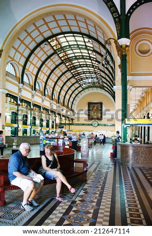 HO CHI MINH, VIETNAM- AUG 21: Beautiful interior in postal center, an ancient french post office with dome design for travel, couple of traveller visit, sit on bench to relax, Vietnam, Aug 21, 2014