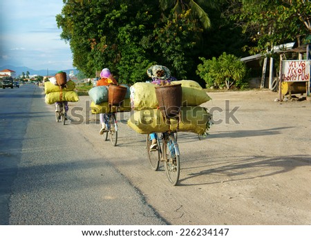 PHAN RANG, VIET NAM- OCT 22: Group of Asian woman ride cycle on highway, women transfer overload bag,  traffic in unsafe situations at Vietnamese country road on day, Vietnam, Oct 22, 2014