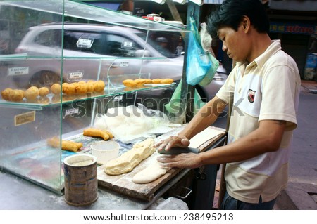 HO CHI MINH CITY, VIET NAM- DEC 17: Vietnamese food at Sai gon street, fried dumplings is popular street food, fast food, family of vendor make dish on pavement, Saigon, Vietnam, Dec 17, 2014
