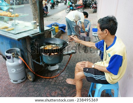 HO CHI MINH CITY, VIET NAM- DEC 17: Vietnamese food at Sai gon street, fried dumplings is popular street food, fast food, family of vendor make dish on pavement, Saigon, Vietnam, Dec 17, 2014