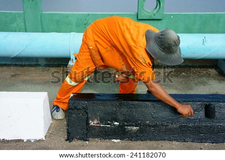 Asian worker working on street, Vietnamese man painting traffic paint on asphalt road, male wear orange work wear, working on day,Ho chi Minh city, Vietnam