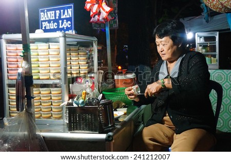 HO CHI MINH CITY, VIET NAM- DEC 29:  Asia cake pavement shop, Vietnamese woman sell creme caramel ( flan cake), street food with sweet, tasty food, lifestyle of city at night, Vietnam, Dec 29, 2014