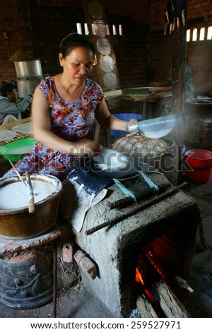 BA RIA, VIET NAM- FEB 11: Asian woman sitting, working at home, Vietnamese female make rice paper from rice flour at banh trang trade village, smoke from firewood cooker, Vietnam, Feb 11, 2015