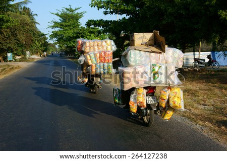 BEN TRE, VIET NAM- MAR 24: Transportation goods on street in danger by motorbike, Asian man ride one hand, carry heavy, overloaded traffic, this is unsafe, can make accident, Vietnam, Mar 24, 2015