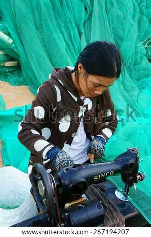 PHAN RANG, VIET NAM- OCT 23: Vietnamese woman working on day, Asian people sew large fishing net, she sitting, work with sewing machine at Tri Thuy, big fishing village, Vietnam, Oct 23, 2014