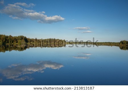 Lake with bright blue sky and clouds reflected in the water