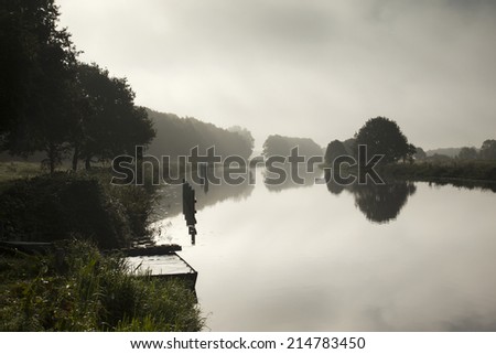 River landscape in the mist with reflections in the water