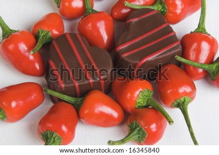 Red Chillies and Heart shaped chocolates on a white background