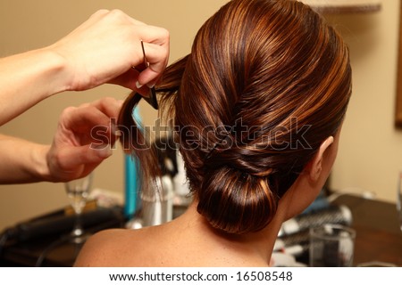 Young bride sitting while a hair stylist is styling her hair