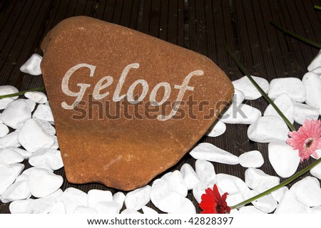 Small sign amongst pebbles with an afrikaans word meaning Faith