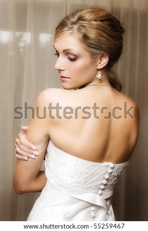 Beautiful Blond bride wearing diamond jewelery looking over her shoulder