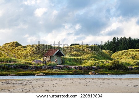 Norwegian cloudy landscape with small house and a river
