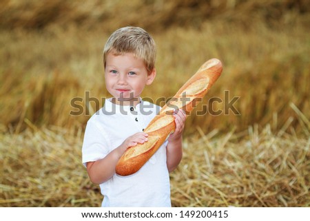 Child with long loaf in the wheat field