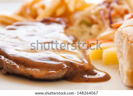 pork chop steak with black pepper gravy bread salad and french fries