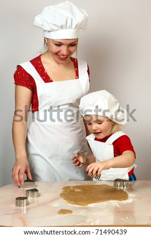 cute daughter with mother in white aprons on kitchen