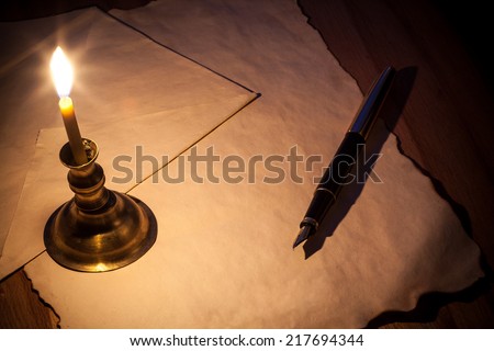 Old paper and pen by the light of candles