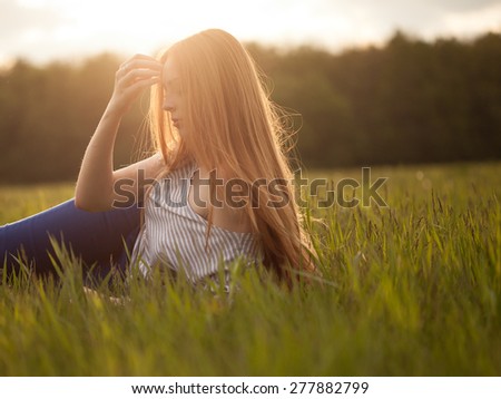 Cute redhead young woman lies on a lawn in the rays of the setting sun