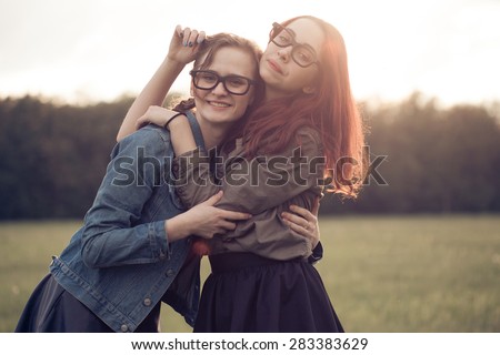 Two girls hug and making fun outdoors