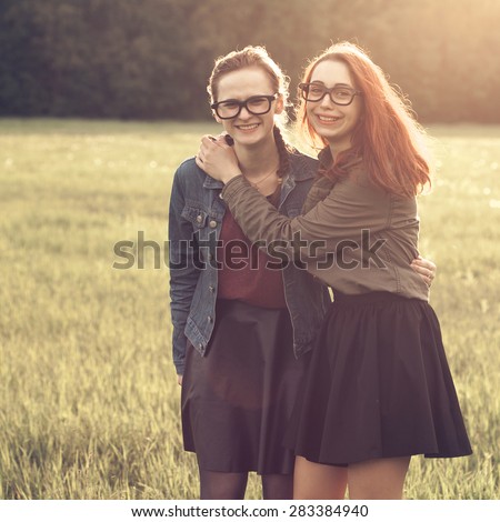 Two girls hug and making fun outdoors