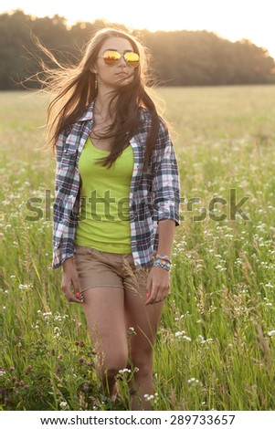 Young active woman  walking in the wind under sunlight of sunset. Vertical