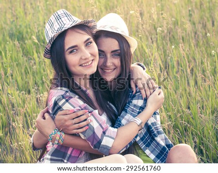 Two beautiful girls in hats outdoors.  Toned
