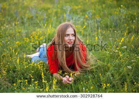 The girl in red is resting on a flower field