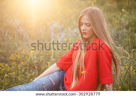 The girl in red is resting in the sunset outdoors