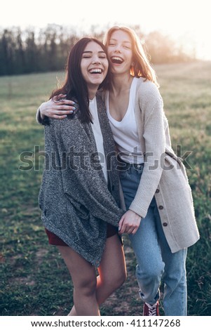 Two girls laughing and hugging outdoors in the evening. Best friends