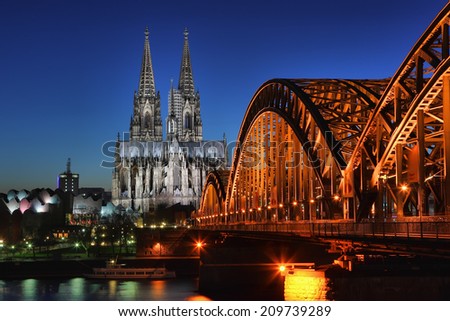 Cologne in the night. Cathedral on the night cloudless blue sky and the railway bridge. Cologne, Germany.