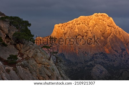 Mountain in orange light Cliff top \'Sokol\' in sunset light against the background of thunderclouds. Photo taken in Crimea in \'Novy Svet\'.