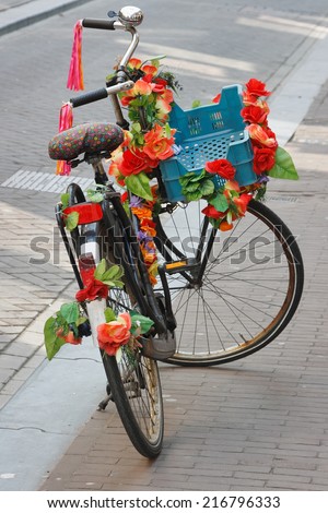 Bicycles of Amsterdam. Parked bicycle with plastic bright red flowers.