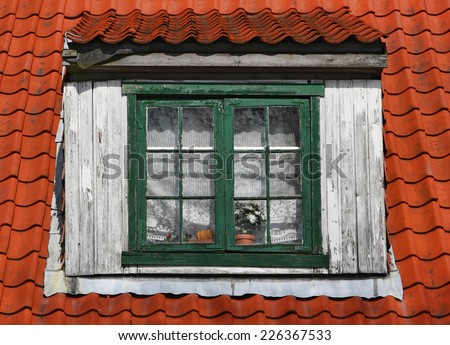 Old window of attic. Window with wooden frame on a tile roof.