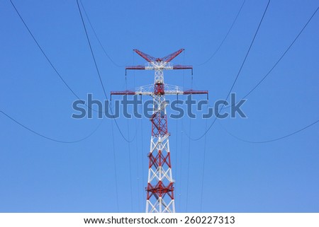Tower of power line on against blue sky. White and red design of the support tower of high-voltage line.