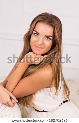 beautiful girl in white dress sitting on a white couch