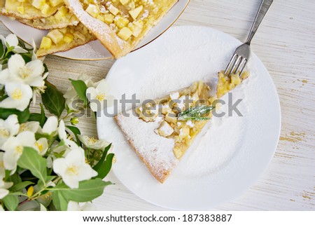piece of apple pie sprinkled with powdered sugar on a white plate
