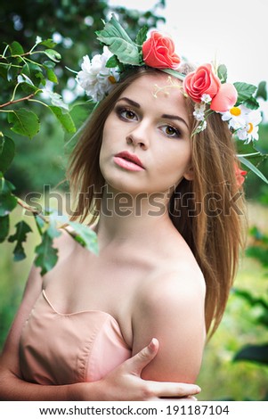 beautiful young blonde woman with flower wreath on his head in the garden
