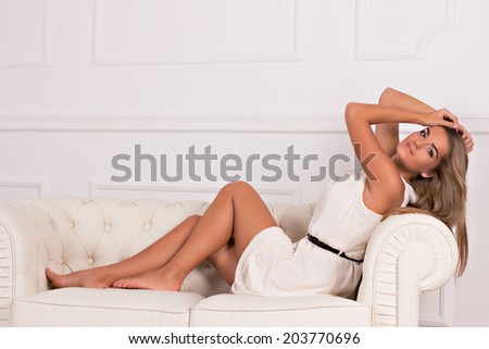 beautiful girl in white dress sitting on a white couch