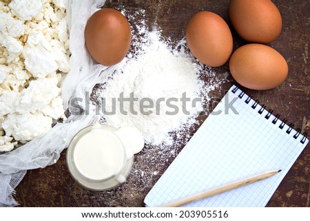 eggs, flour, sour cream, cottage cheese and notepads recipes are on the old table