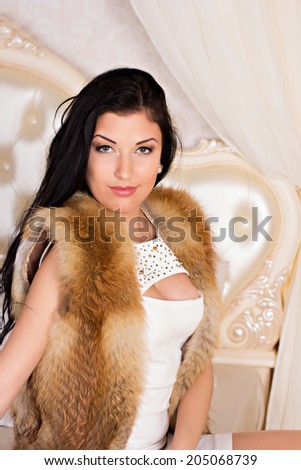 beautiful dark-haired young woman in a white dress and a fur vest
